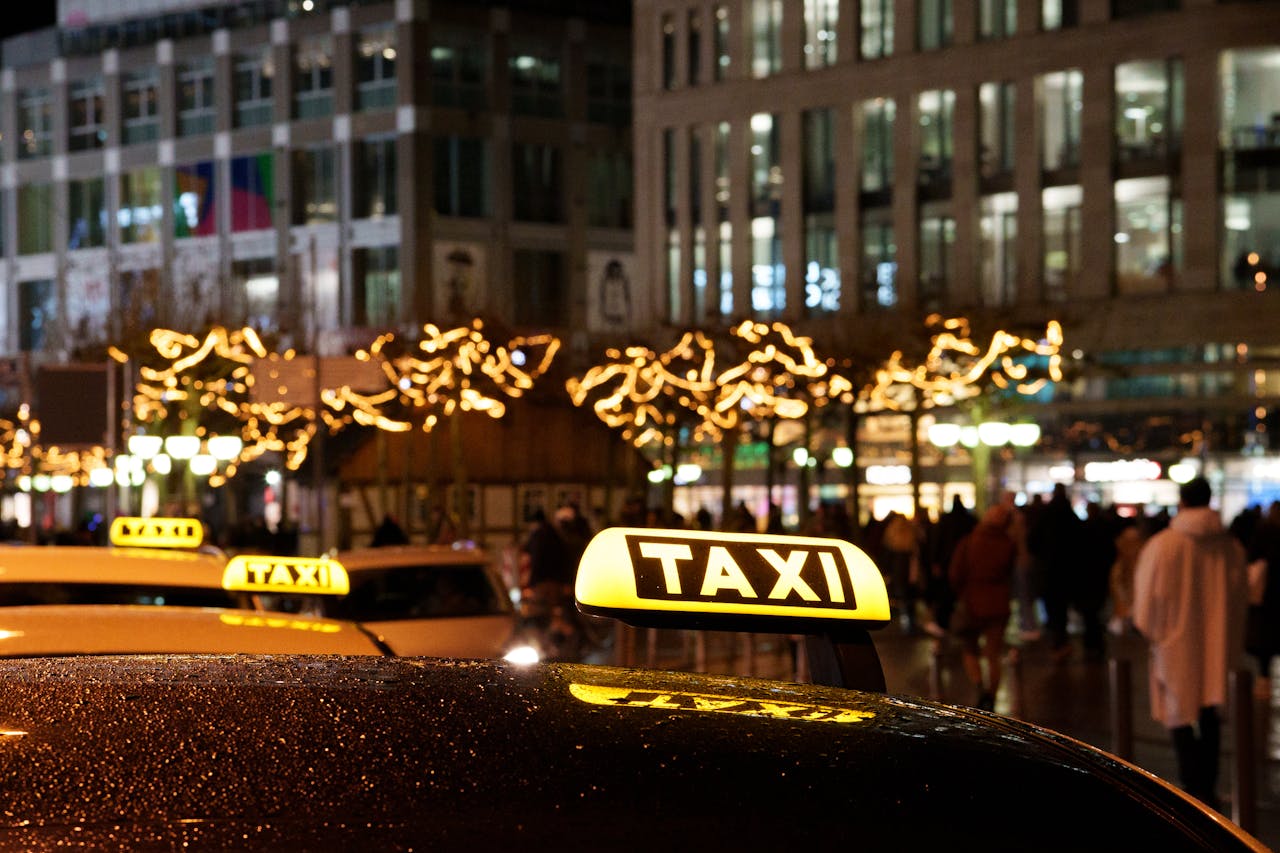 A vibrant city scene at night featuring taxis with illuminated signs and festive decorations.